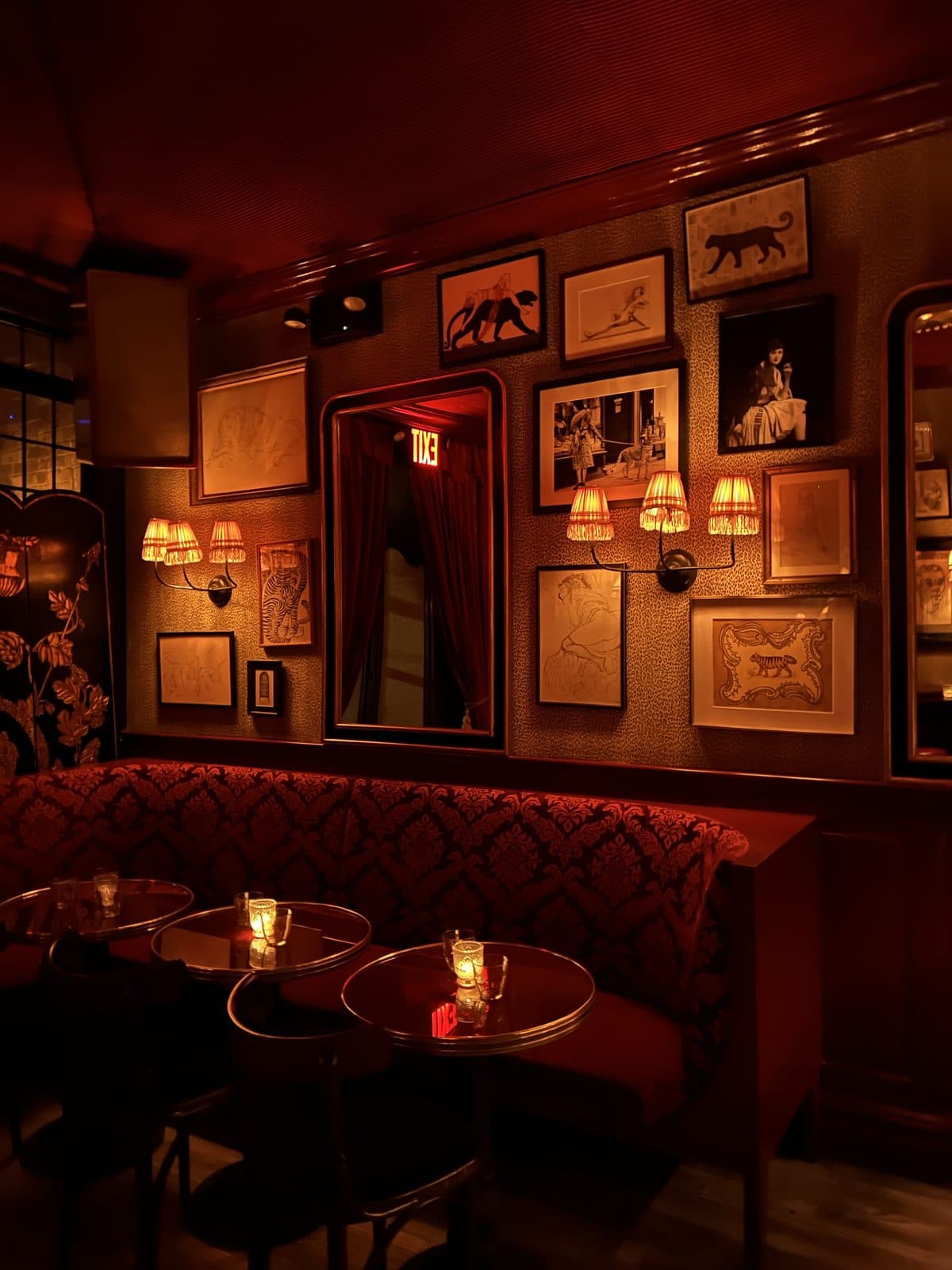 An intimate candlelit restaurant room with small tables and gallery walls