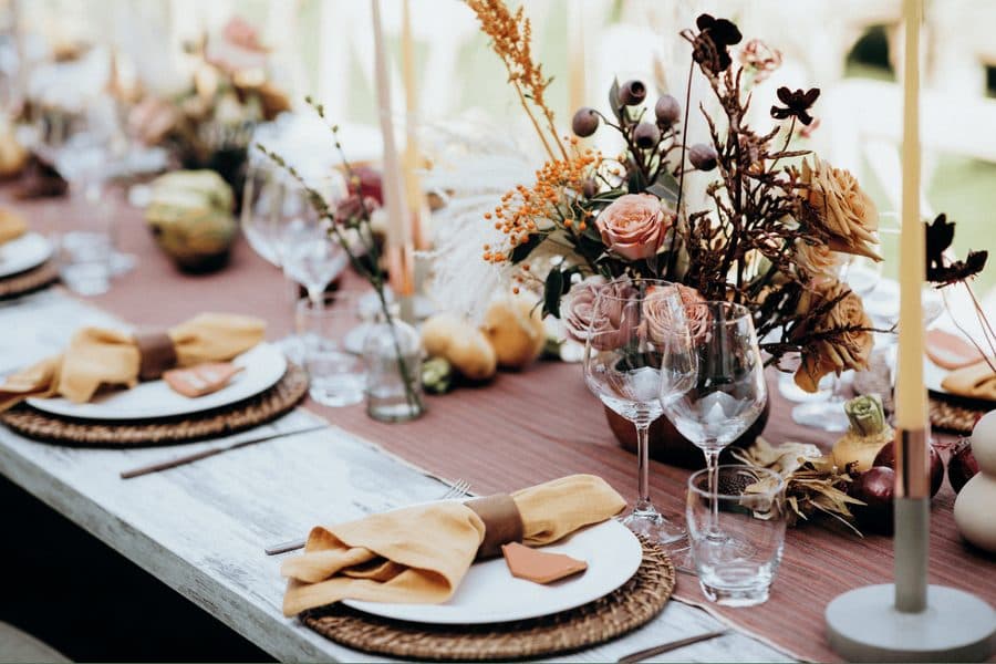 A reception table set with dried florals, candles and woven chargers
