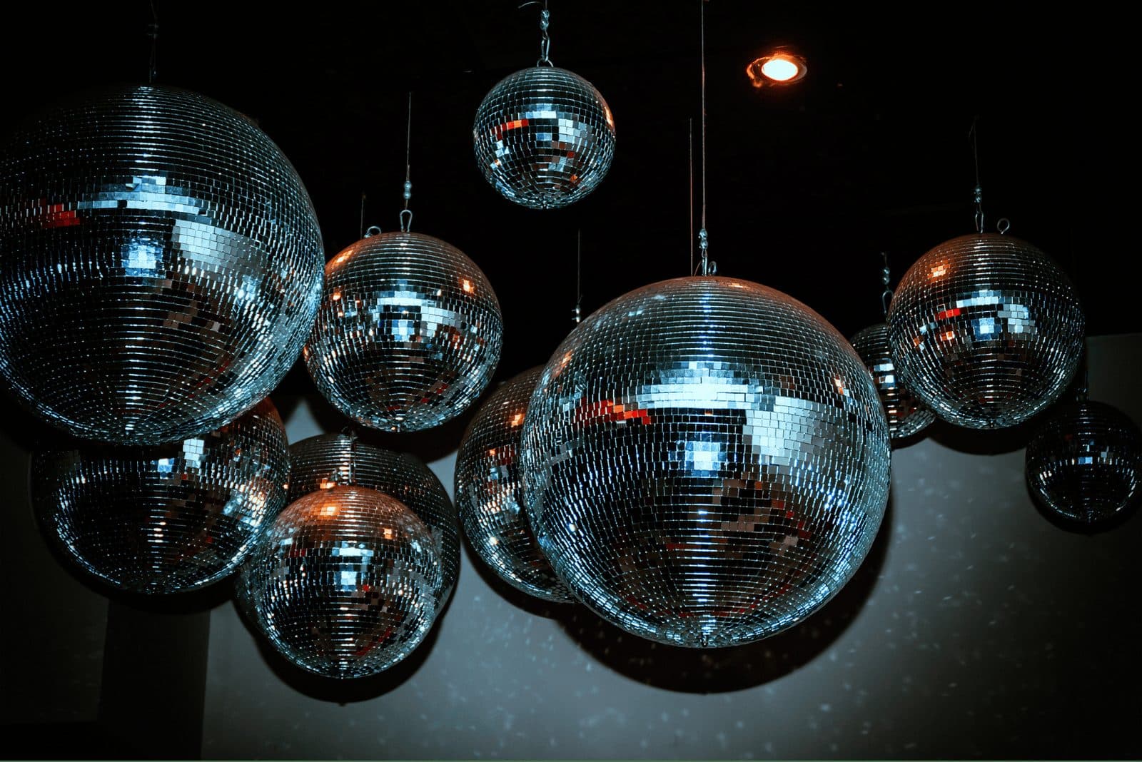 A cluster of disco balls hanging above a dark dance floor