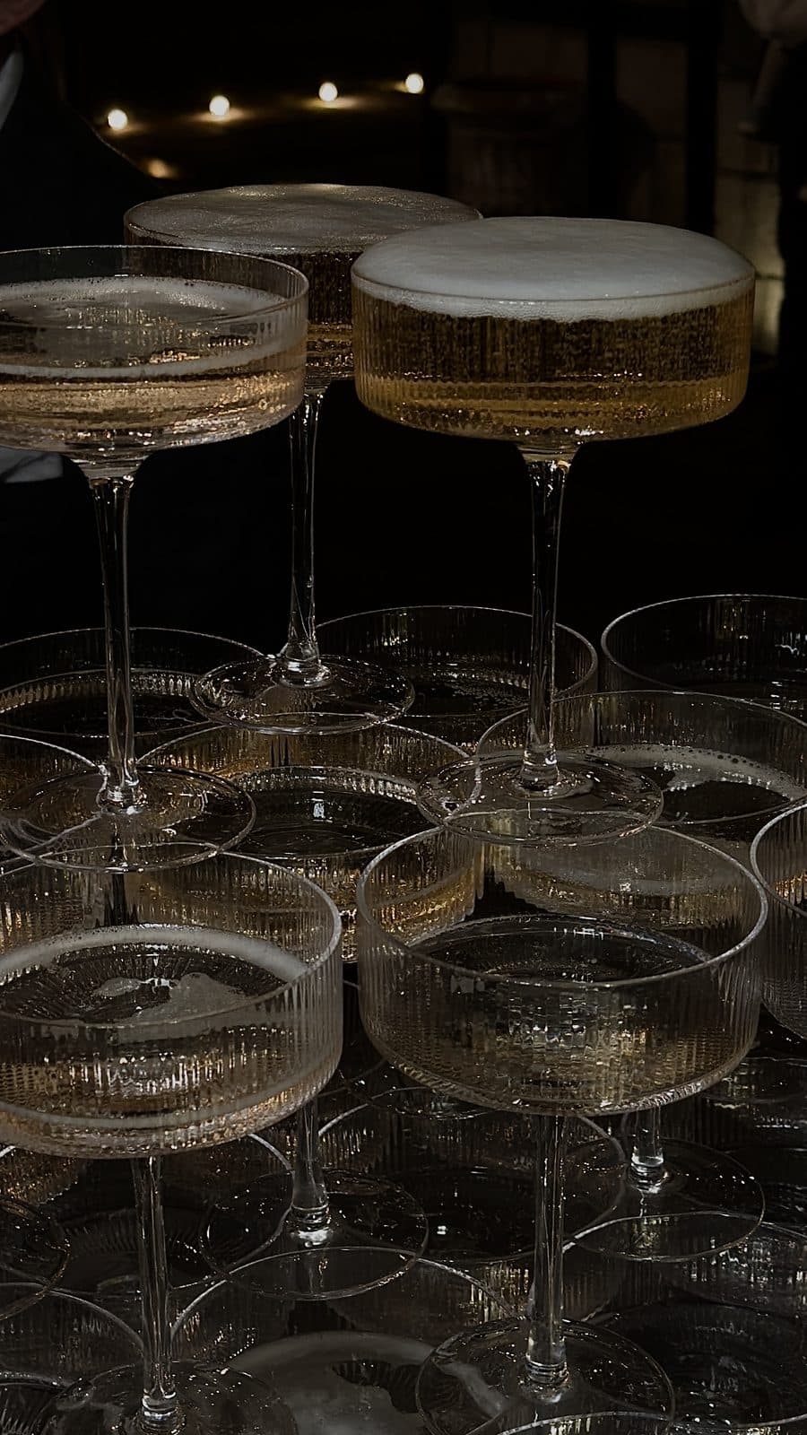 Rows of coupe glasses stacked and filled with champagne before a reception
