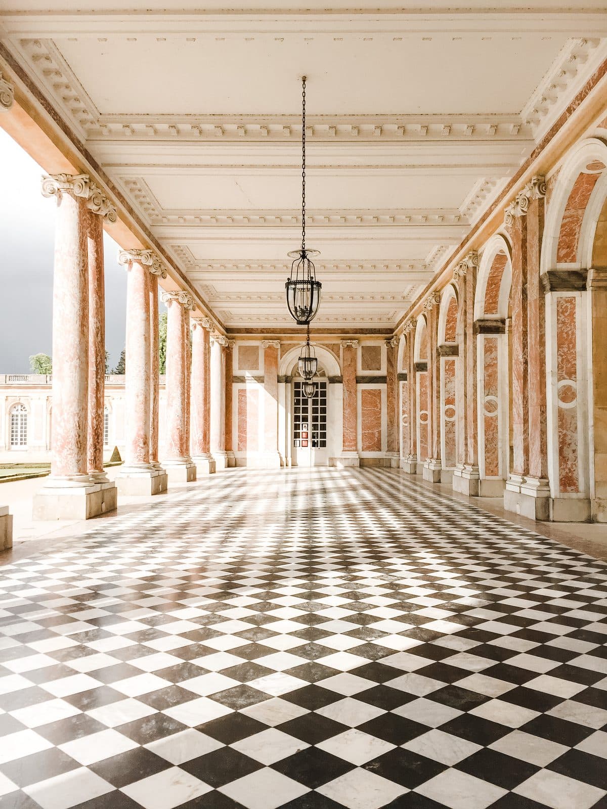 An empty grand hall with columns, arches and a checkered marble floor